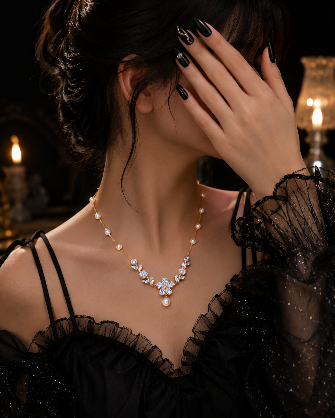 A woman in a black lace dress wears a delicate necklace with a floral crystal centerpiece and small pearl-like beads, posed against a dark, candle-lit background.