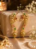 A pair of ornate gold-toned traditional earcuff earrings with green, red, and white gemstone accents